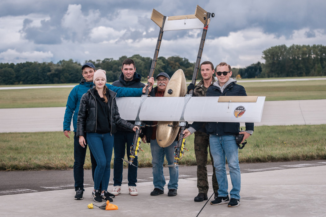 Bohaterka tekstu stoi na płycie lotniska wraz z zespołem trzymając bezzałogowy system powietrzny Stefan-1