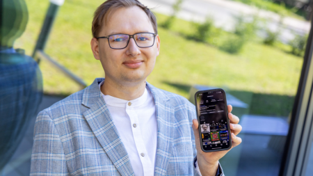 mgr inż. Mateusz Majszyk z telefonem na którym widać jego popularnonaukowy profil na instagramie. Telefon z otwartym profilem #młodegoinnoWATora na Instagramie. Edukacja naukowa jest promowana na Instagramie.