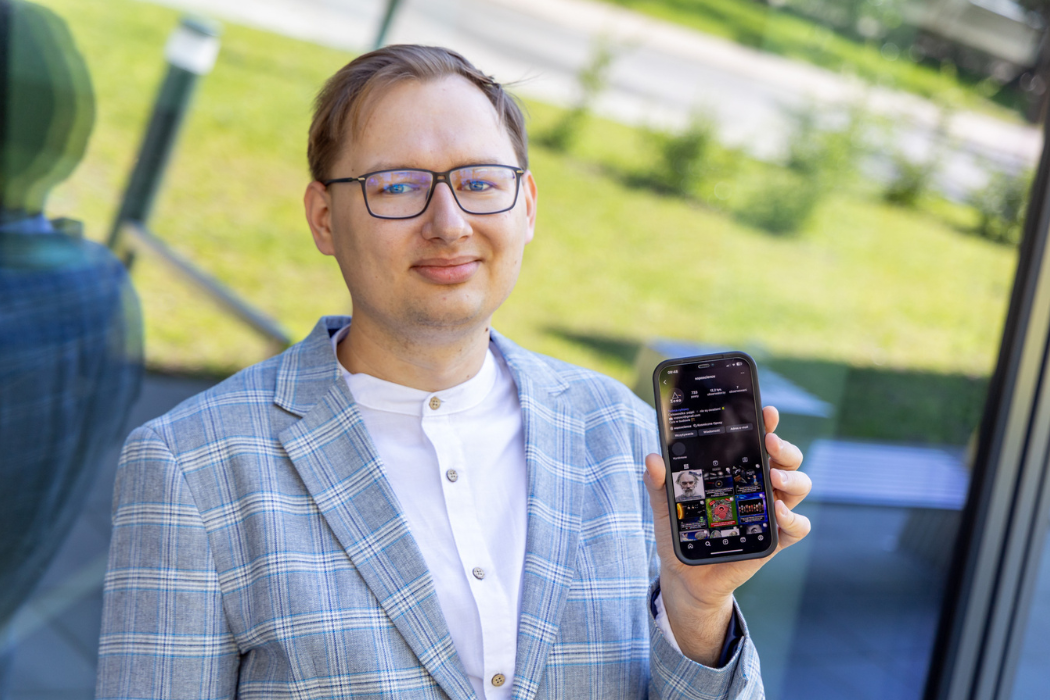mgr inż. Mateusz Majszyk z telefonem na którym widać jego popularnonaukowy profil na instagramie. Telefon z otwartym profilem #młodegoinnoWATora na Instagramie. Edukacja naukowa jest promowana na Instagramie.